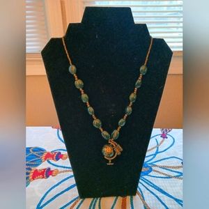 Dark green and gold beaded necklace with globe and binoculars pendant.